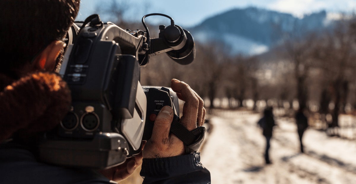 Photographer capturing pair of people walking along bare trees in winter