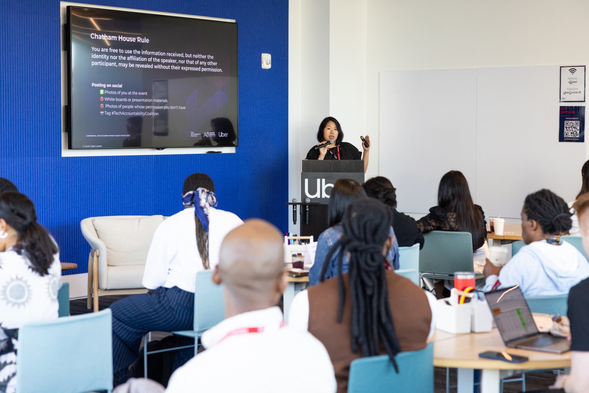 A woman speaks at a podium in front of seated participants at the Product Equity Offsite.